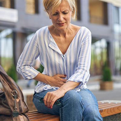 lady sitting on bench with stomach pain