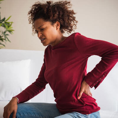 woman with back pain on couch