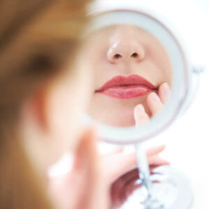 Woman looking at lips in mirror