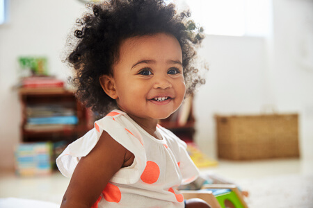 little baby girl smiling in bright playroom