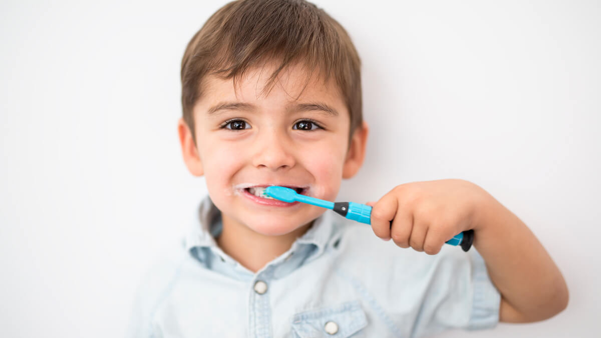 little boy brushing his teeth and smiling