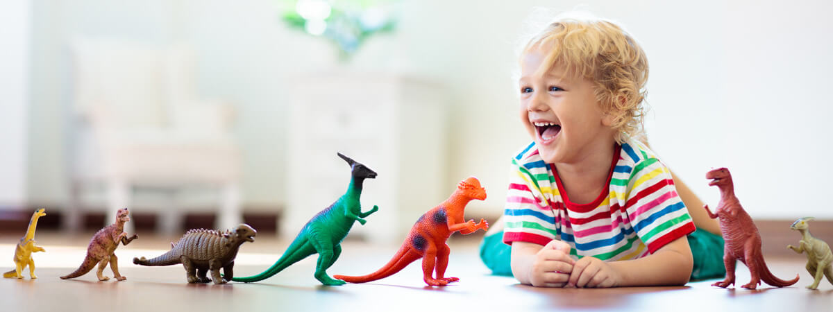 little boy playing with dinosaurs on the ground