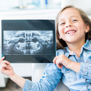 little girl holding teeth x-ray