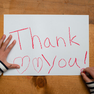 child hands writing thank you sign and hearts