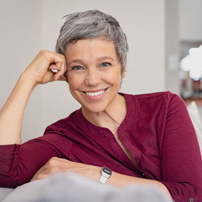 Mature woman leaning on a couch and smiling