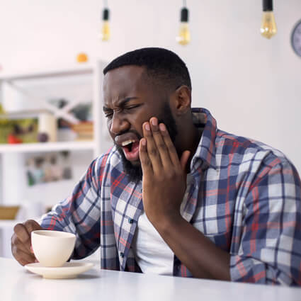 man having coffee touching mouth in pain