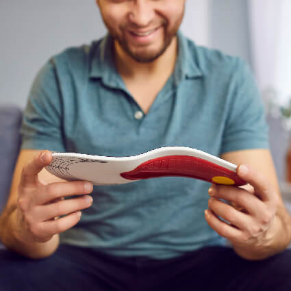 Man holding orthotics in his hands