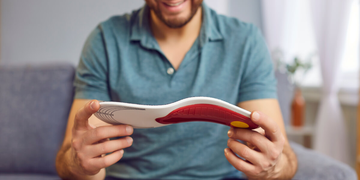 Smiling man holding custom orthotics