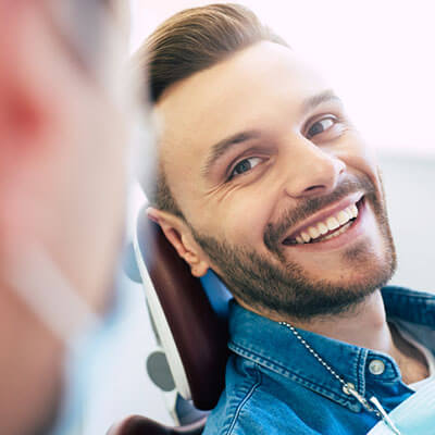 man smiling at dental visit sitting on dental chair