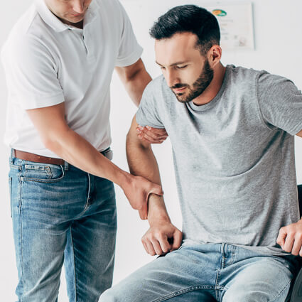 Chiropractor assisting patient with post-surgical rehabilitation and strength recovery