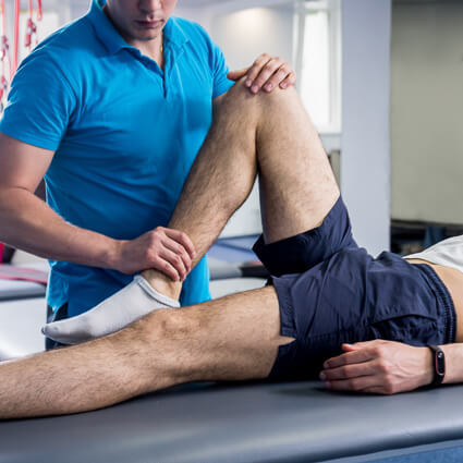 Man in shorts laying on table during physical therapy on knee