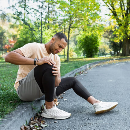 man sitting on a curb with knee pain