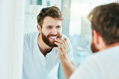 Man looking at teeth in mirror