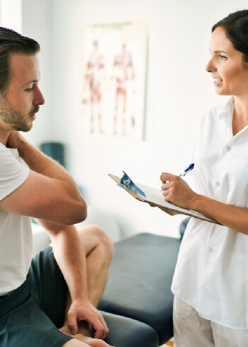 man on adjustment table talking with chiropractor about shoulder pain