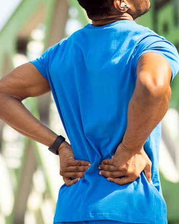 Man outdoors holding his lower back in pain