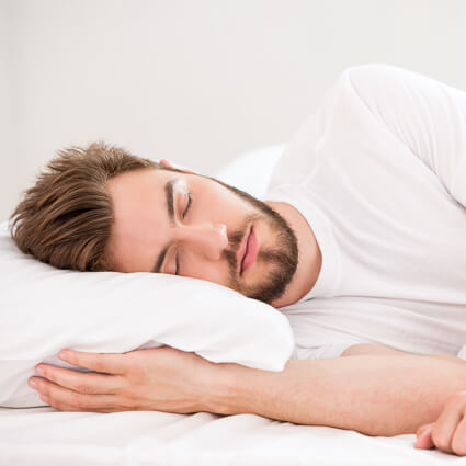 Man sleeping on side with hand under pillow