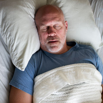 older man asleep in bed