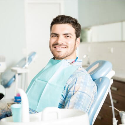 man smiling in dental chair behind instruments