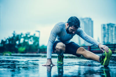 Male athlete stretching his legs in the rain