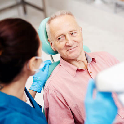 Older man wearing pink shirt sitting in dentist's chair