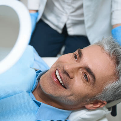 Man happily looking in the mirror at his new smile