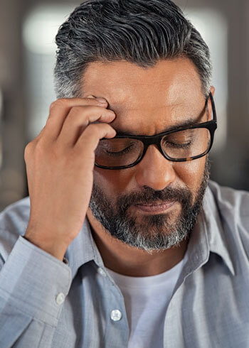 man wearing glasses with head pain 