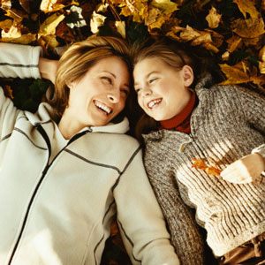 Mother and daughter laying in the leaves. 