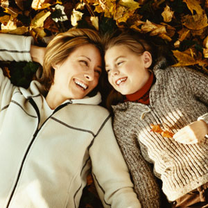 mom and daughter laying in leaves smiling