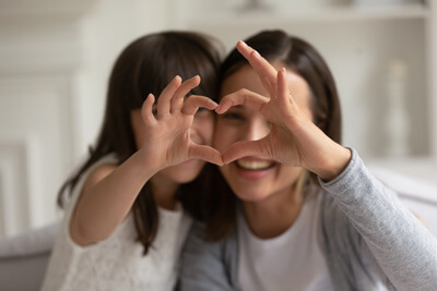 Mom and girl making heart with hands