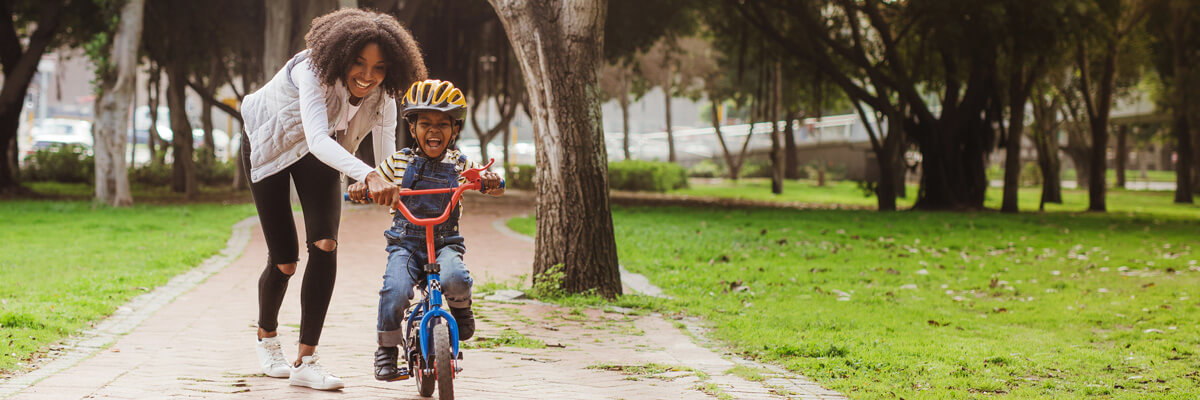 Mom teaching young son how to ride a bicycle