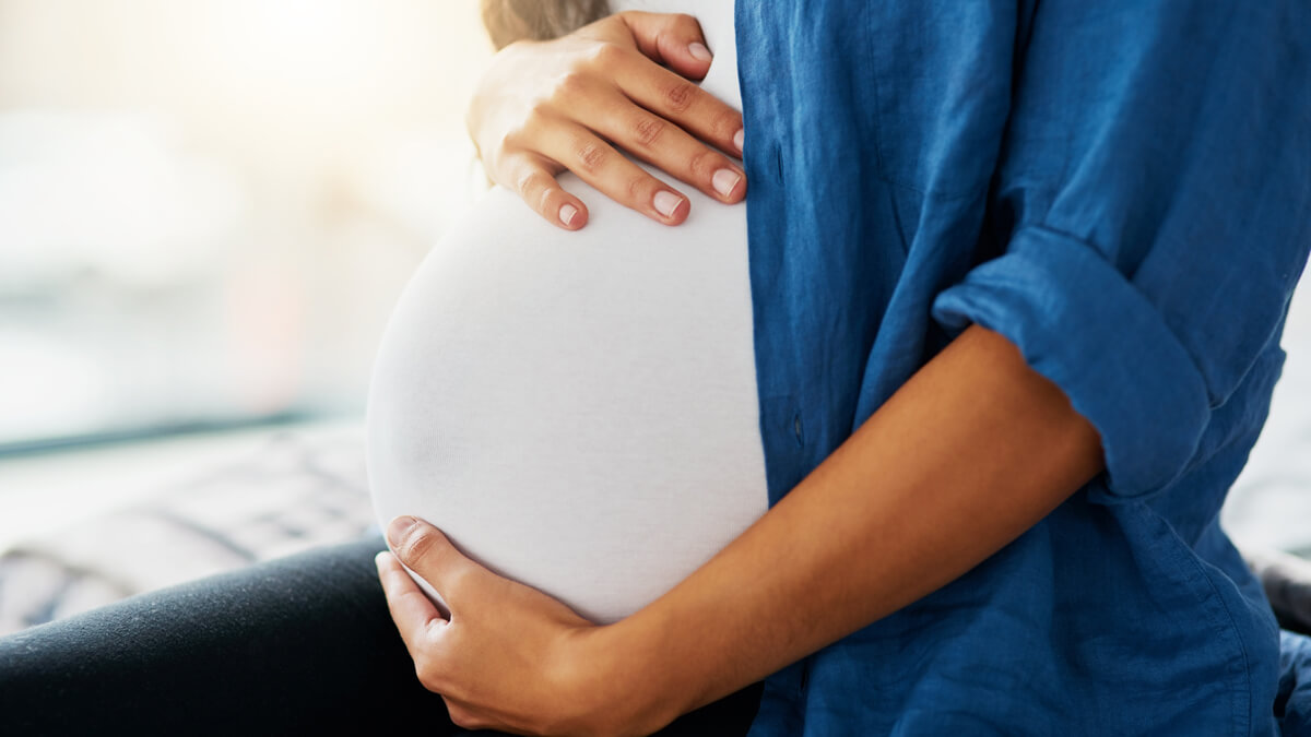 Woman with hands around pregnant belly