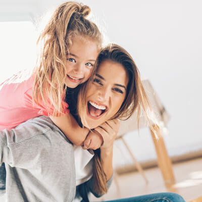 lady with daughter on back laughing
