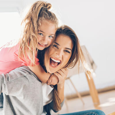 Toddler daughter on moms back smiling