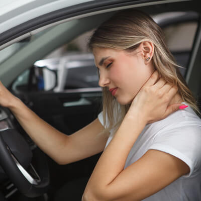 woman holding neck in pain in car