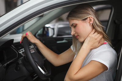 Female with neck pain sitting in car