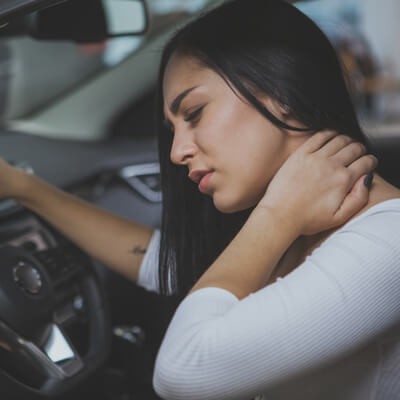 Woman holding her neck in pain while sitting in a car