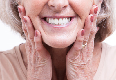 older woman holding cheeks smiling