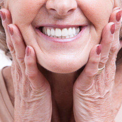 older woman holding cheeks smiling