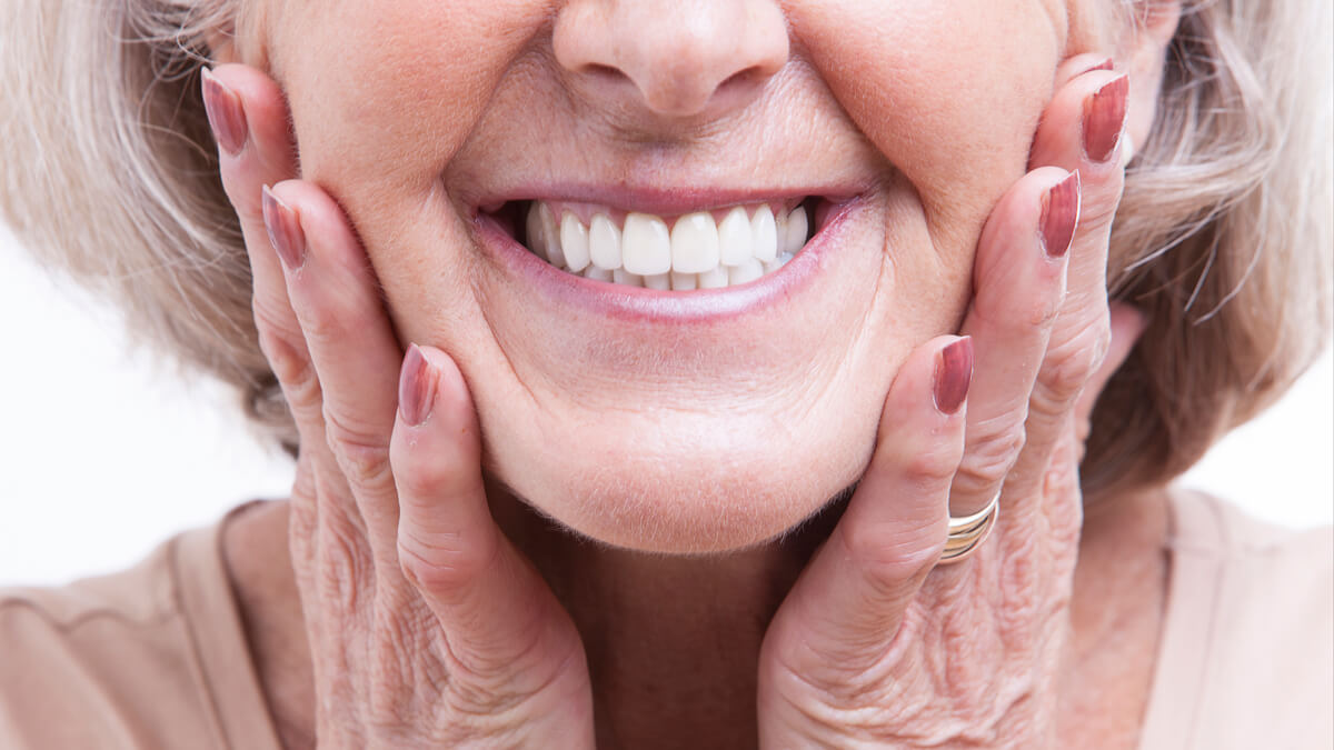 closeup of older woman holding cheecks and smiling