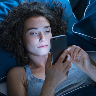 Woman looking at phone in bed