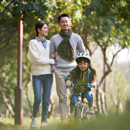 mom and dad walking while their daughter rides her bike