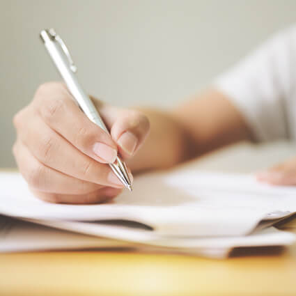 person filling out forms with a pen