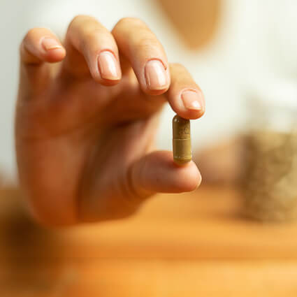 Person holding supplement capsule between fingers