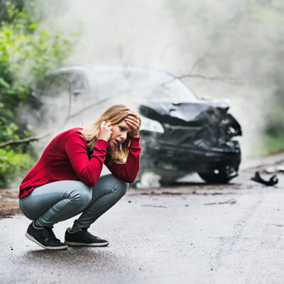 woman kneeling after car accident