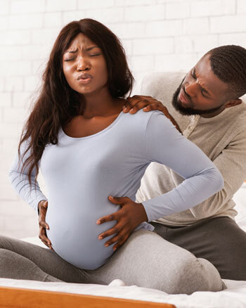 Pregnant couple on bed in pain