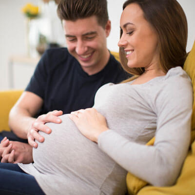 A pregnant woman and her partner smiling at her belly