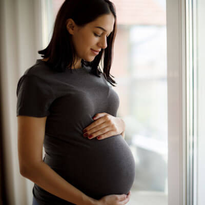 Pregnant woman smiling at her pregnant belly.