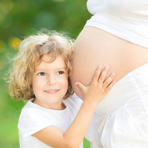 Child resting head on mother's pregnant belly