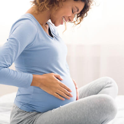 Woman smiling at her pregnant belly