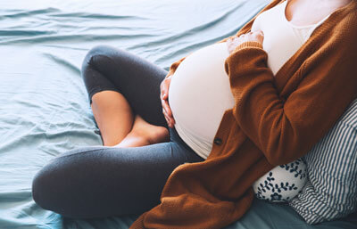 Pregnant woman sitting on bed